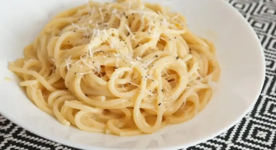 Pyszne spaghetti carbonara przepis na talerzu, posypane parmezanem i świeżo mielonym pieprzem.