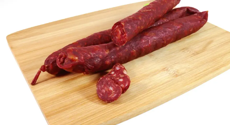 Kilka kawałków chorizo na desce do krojenia. To pikantna, suszona kiełbasa wieprzowa, idealna do tapas.