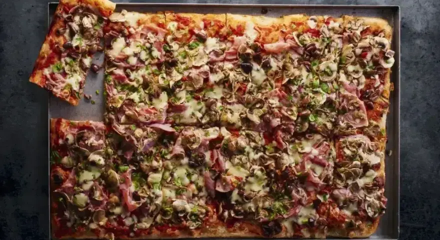 Pyszna pizza domowa przepis na blachę z szynką, pieczarkami i oliwkami. Idealna na rodzinne spotkanie.