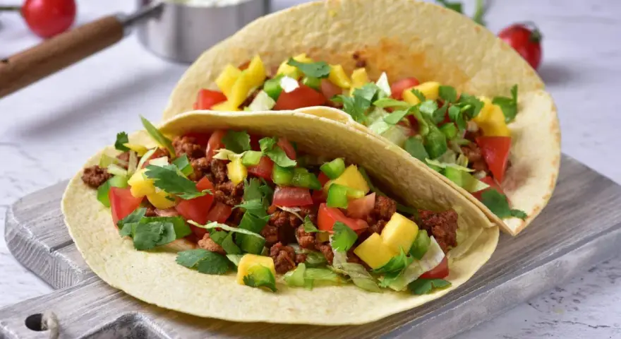 Dwa pyszne, domowe fast foody: tortille z mielonym mięsem, pomidorami, papryką, mango i świeżą kolendrą.