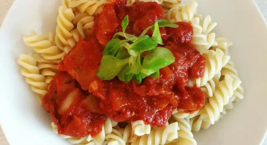 Szybki obiad z makaronem fusilli i sosem pomidorowym, udekorowany świeżą zieleniną. Idealny na szybki posiłek.