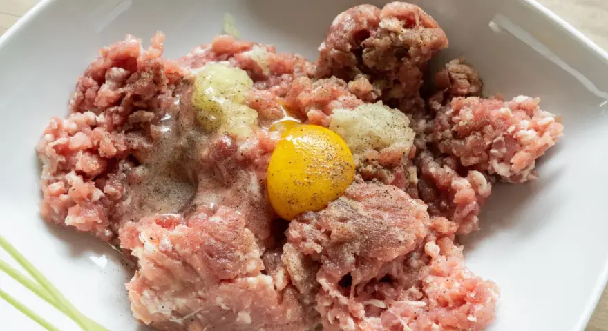 Mielone mięso z dodatkiem cebuli i jednego jajka, gotowe do dalszego przygotowania. Ile jajek do mielonych? Zazwyczaj jedno na pół kilograma mięsa.