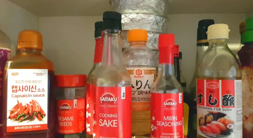 Butelka z napisem "MIRIN SEASONING" obok sosu do sushi i sake. Mirin co to? To japońska przyprawa do gotowania.