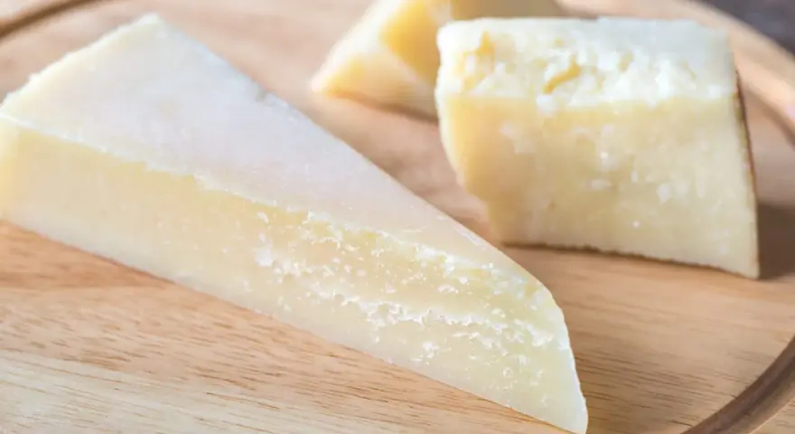 Kawałki twardego, żółtego sera na desce. Szukasz pomysłów, czym zastąpić parmezan?