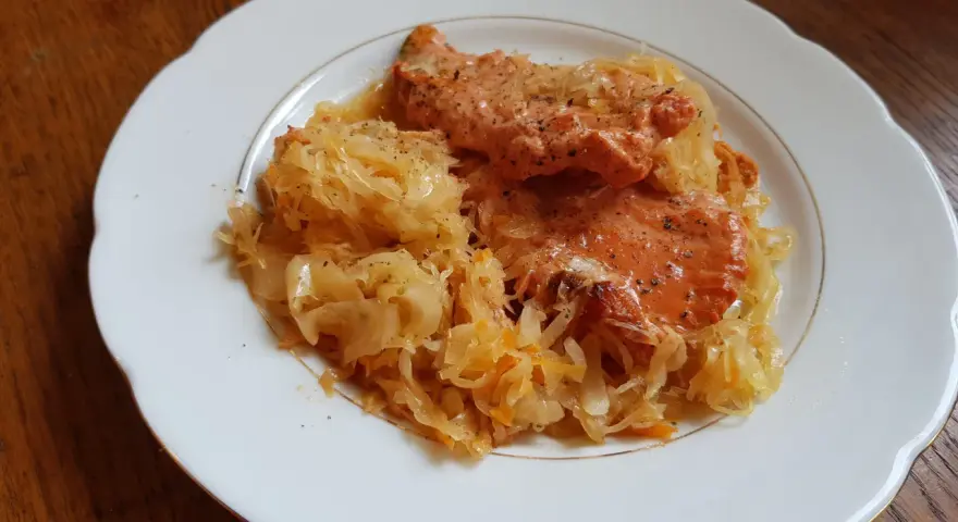 Schab w kapuście kiszonej, danie Ani, wygląda apetycznie na białym talerzu.