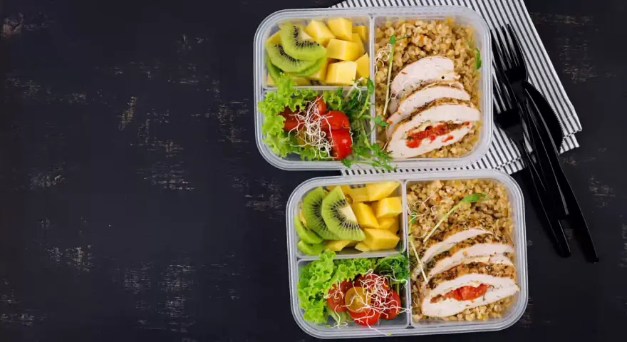 Dwa pudełka na lunch do pracy: kurczak faszerowany, kasza, sałatka z pomidorkami i kiełkami, kiwi i mango.