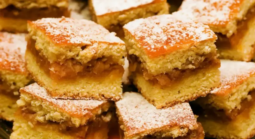 Szybkie ciasto z jabłkami, pokrojone w kostkę i posypane cukrem pudrem, wygląda apetycznie.