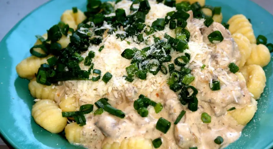 Pyszne gnocchi z kurczakiem w kremowym sosie, posypane parmezanem i szczypiorkiem.