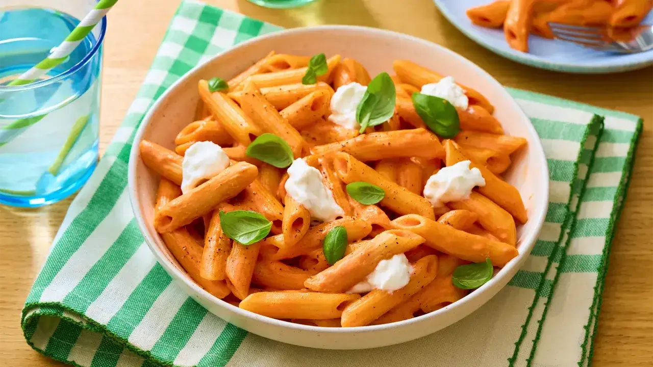 Penne w kremowym sosie pomidorowym z kawałkami mozzarelli i listkami bazylii. Idealny makaron z mozzarellą na szybki obiad.