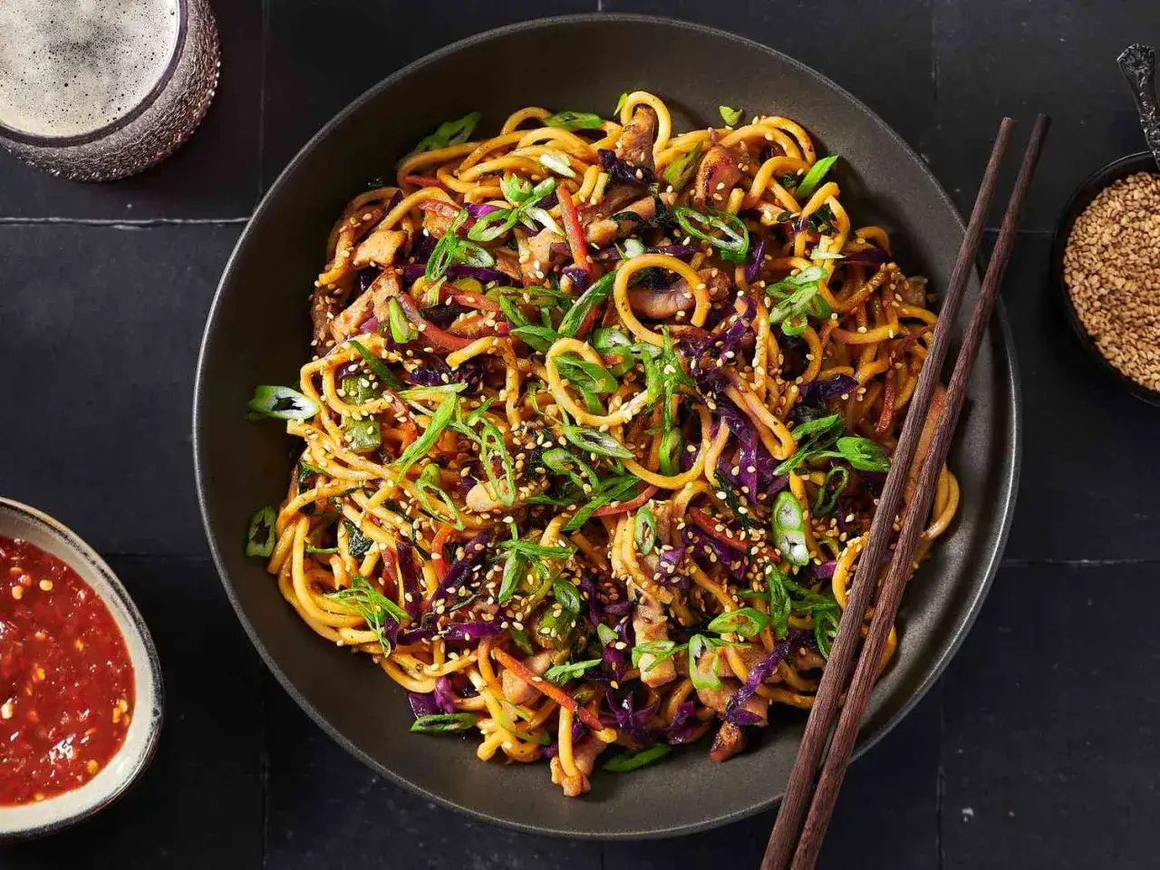 Pyszny makaron chow mein z kurczakiem, warzywami i sezamem, gotowy do jedzenia pałeczkami.