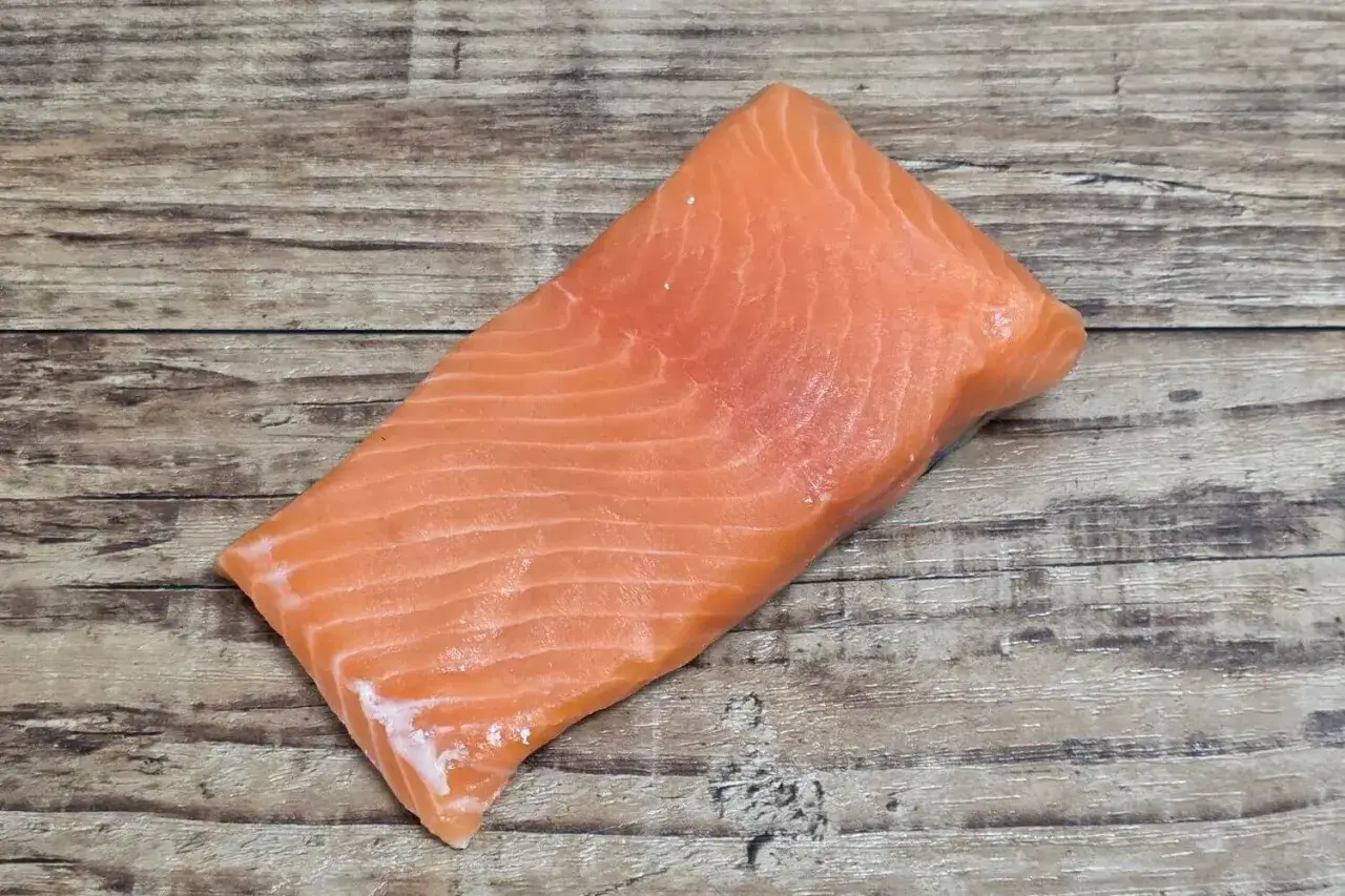 Idealny łosoś do sushi: świeży, soczysty kawałek ryby o pięknym, pomarańczowym kolorze, ułożony na drewnianym tle.