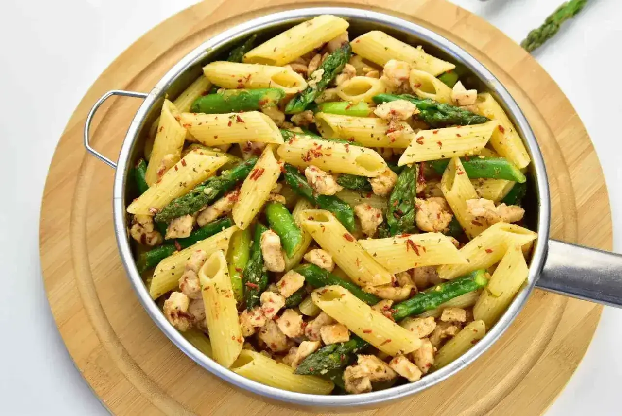 Penne z kurczakiem i zielonymi szparagami, posypane papryką. Pyszne danie, które zachwyci każdego miłośnika makaronu.