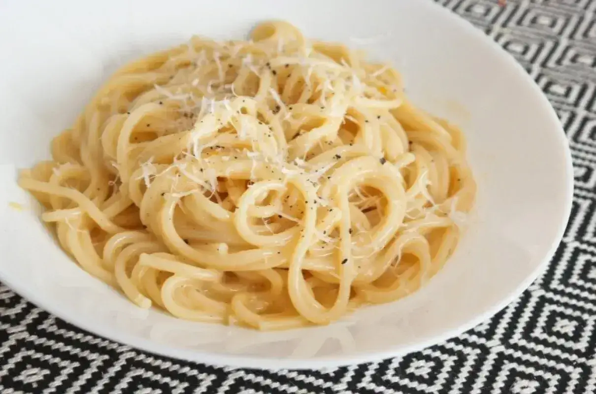 Pyszne spaghetti carbonara przepis na talerzu, posypane parmezanem i świeżo mielonym pieprzem.