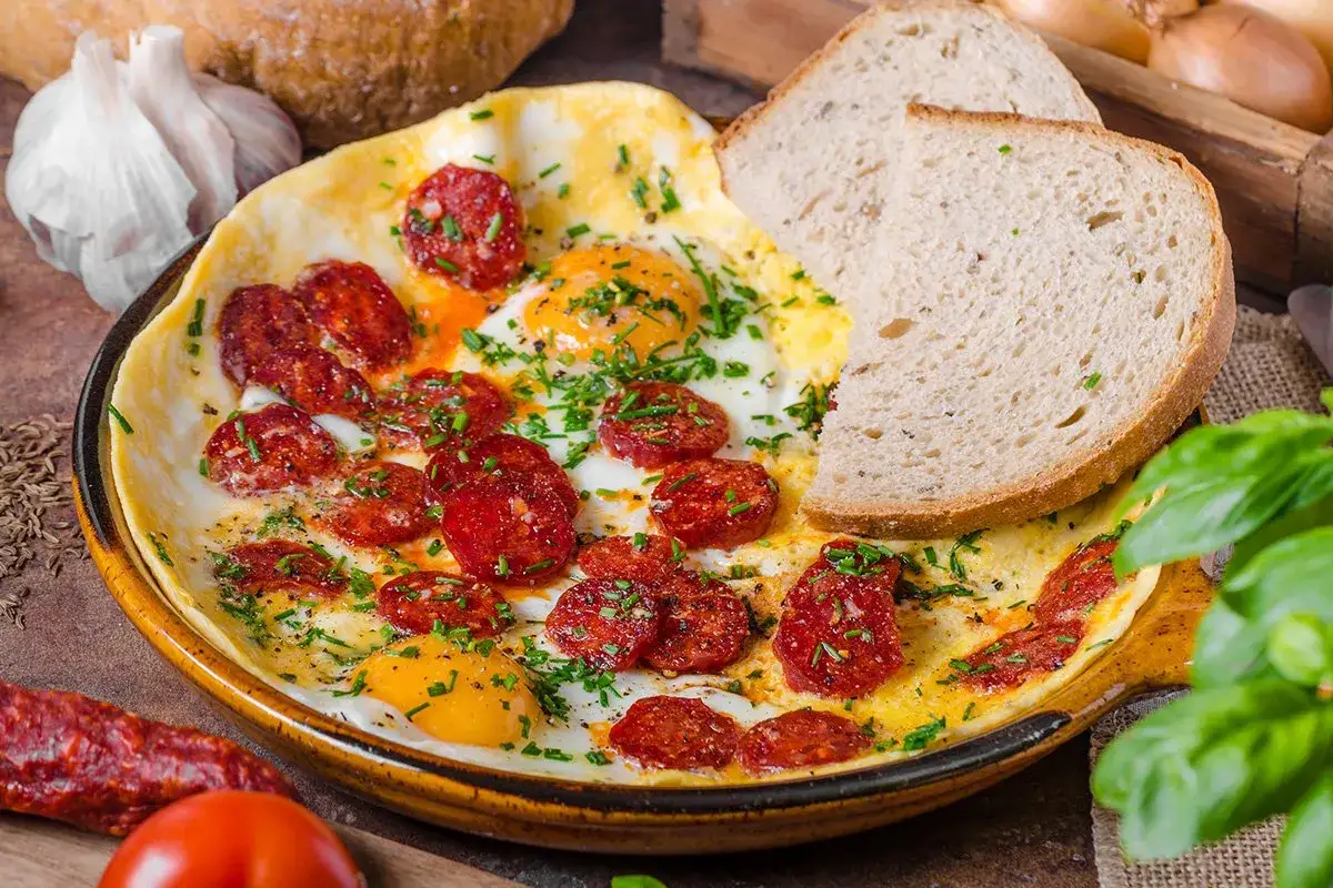 Jajecznica z chorizo, posypana szczypiorkiem, podana z chlebem. Pyszne śniadanie, które rozwieje wątpliwości: chorizo co to jest - to dodatek, który wzbogaci każde danie!