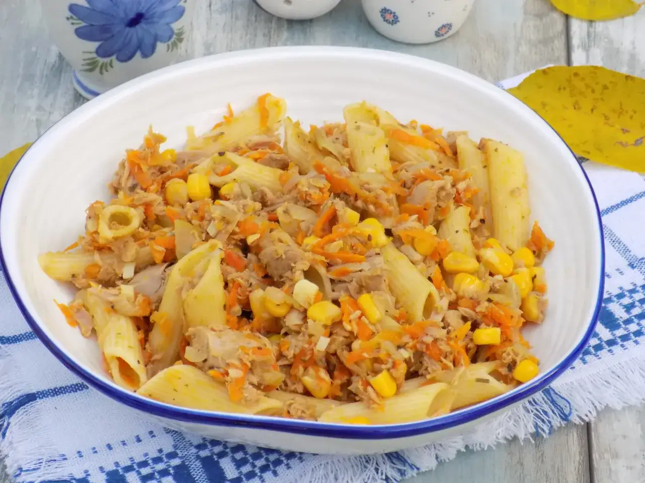Penne z tuńczykiem, kukurydzą i startą marchewką w białej misce. Pyszne danie na szybki obiad.