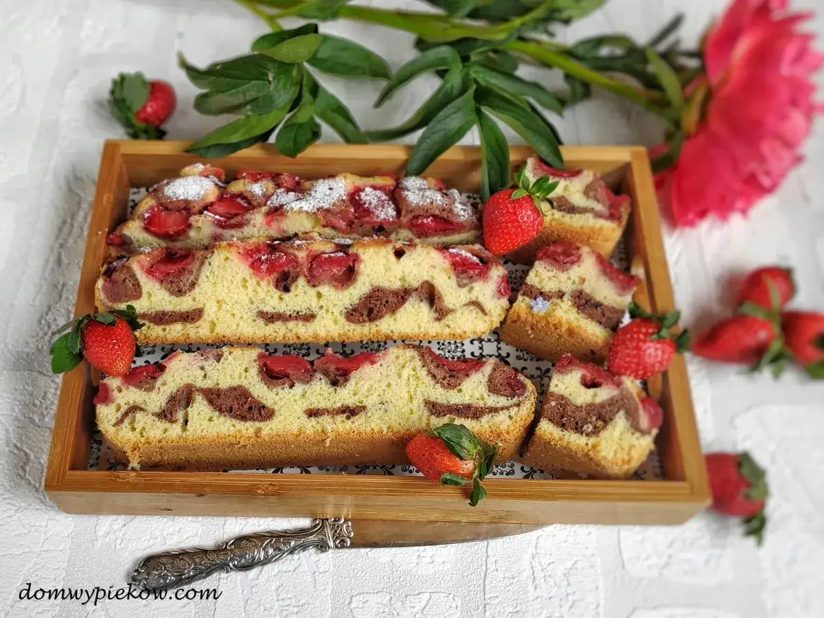 Oszałamiające ciasto z truskawkami, z czekoladowymi wirami, na drewnianej tacy, ozdobione świeżymi owocami i kwiatem piwonii.