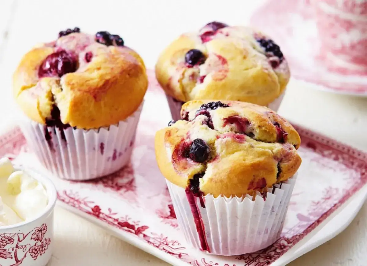 Puszyste muffinki z borówkami, z soczystymi owocami w środku, kuszą apetycznym wyglądem.