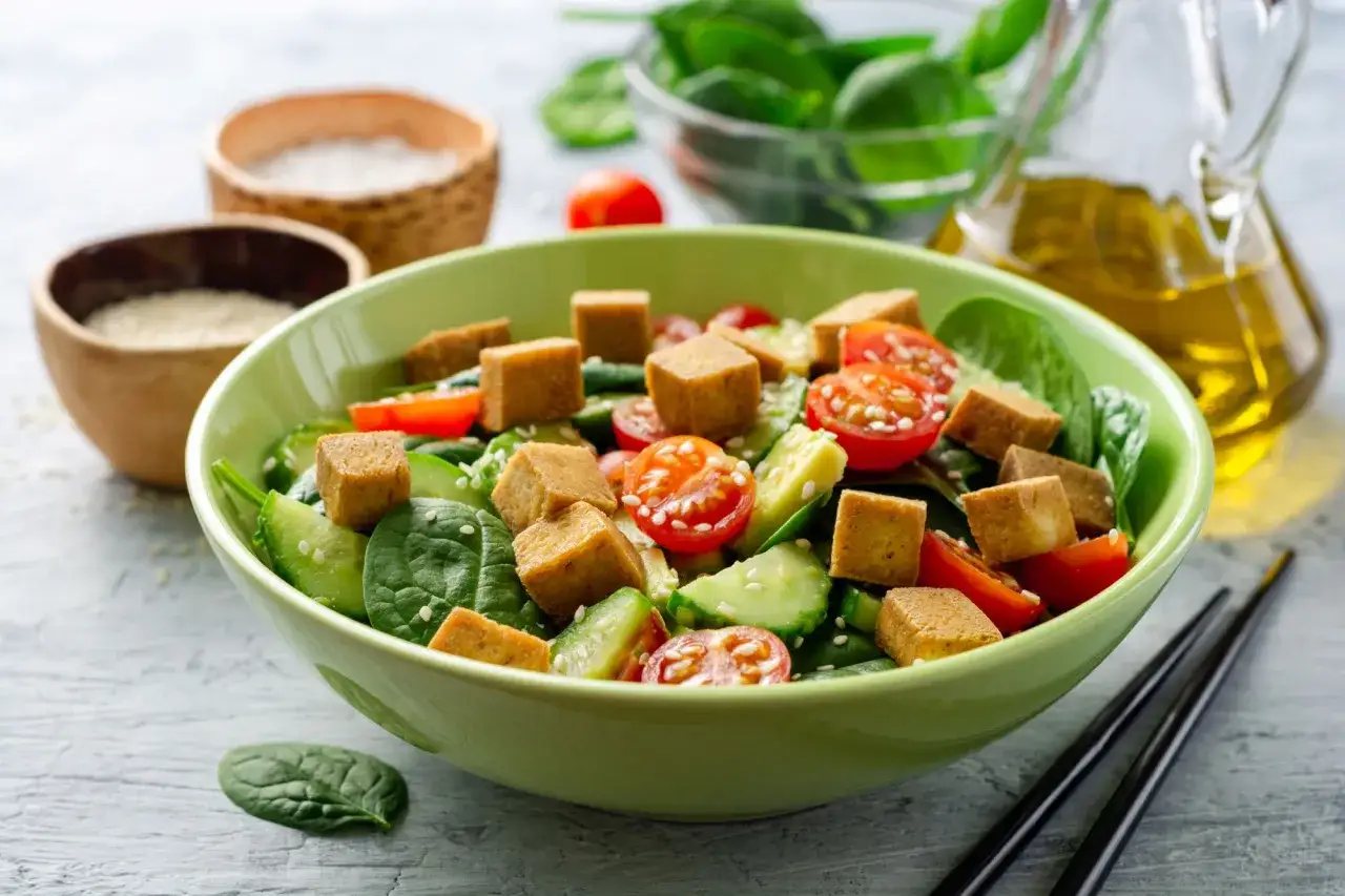 Sałatka ze świeżych warzyw i kostek tofu. Czy tofu można jeść na surowo? Tak, w tej pysznej sałatce z pomidorkami, ogórkiem i szpinakiem.